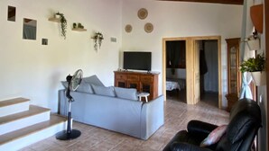 Un salon avec un canapé, un ventilateur, un téléviseur et un fauteuil en cuir.