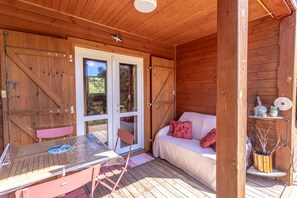 En træhytte med skydedør, et bord med stole, en sofa med puder og en lille hylde med dekorative genstande.