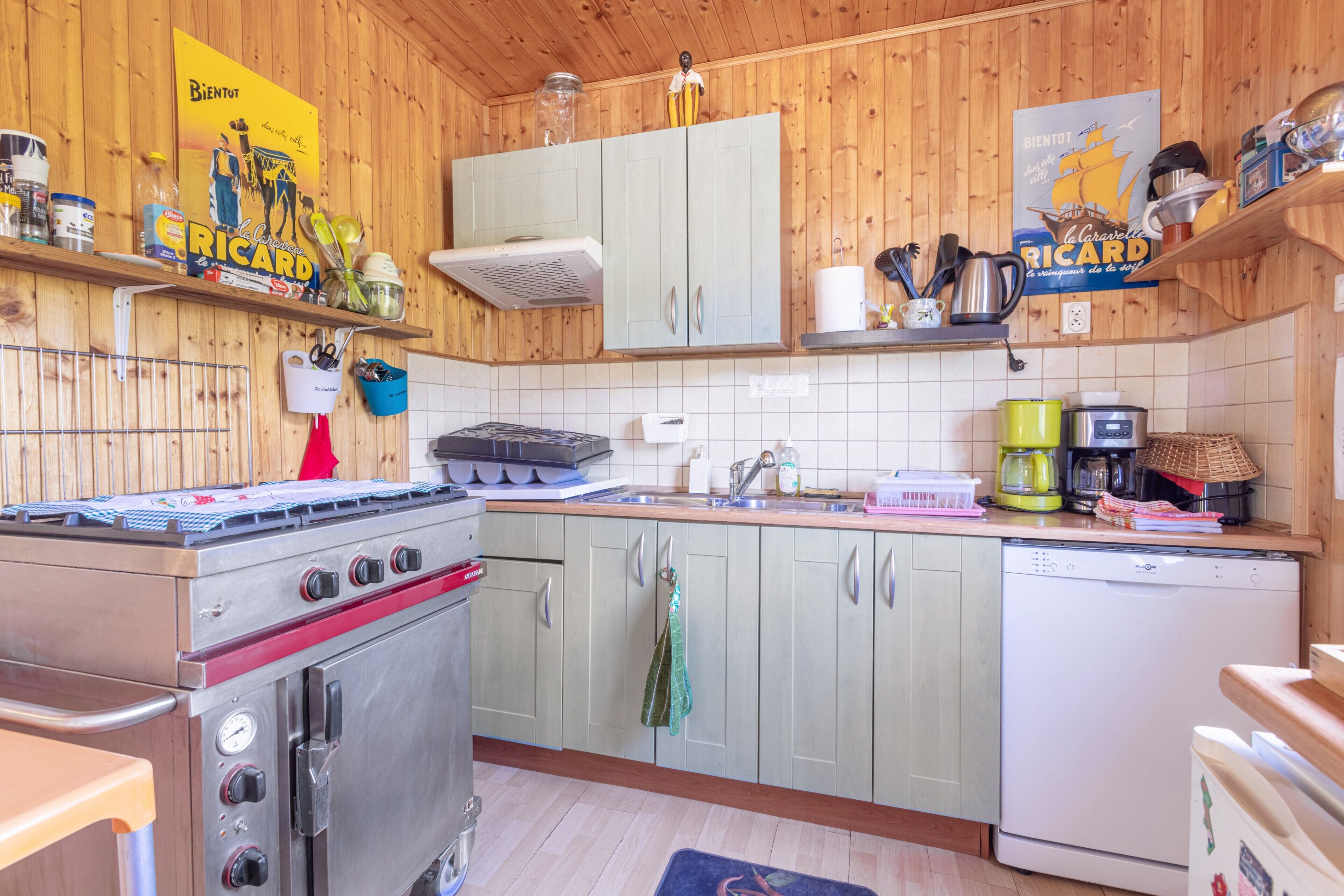 Une cuisine dotée de meubles de rangement en bois, d’une cuisinière, d’un lave-vaisselle et de divers ustensiles de cuisine.