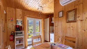 A wooden cabin interior with a dining table, chairs, a kitchen area, and a fire extinguisher.