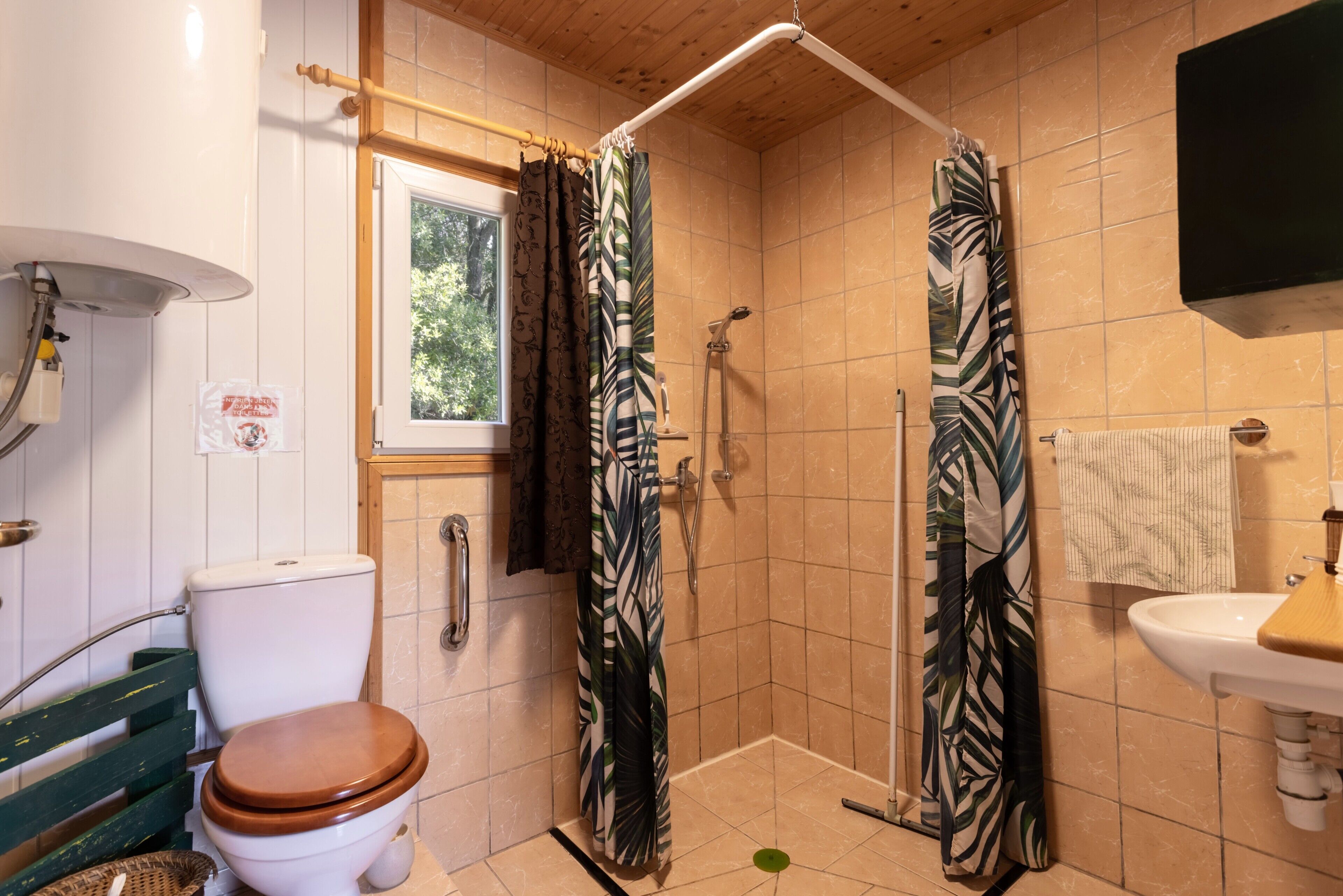 A bathroom with a toilet, shower, sink, and a window.