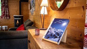 Ein Holzinnenraum mit einem gerahmten Bild von einem Berg, einer Lampe und einer gemütlichen Sitzecke.