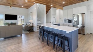 A modern kitchen with a large island, bar stools, and stainless steel appliances. - NEW HOME! AMISTAD IS AN UPSCALE 6BD/4BA HOME W/GULF & CANAL VIEWS, PRIVATE POOL! (Mexico Beach)