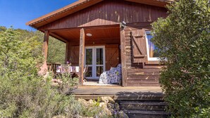 A wooden cabin with a porch, a door, and a small table with chairs outside.