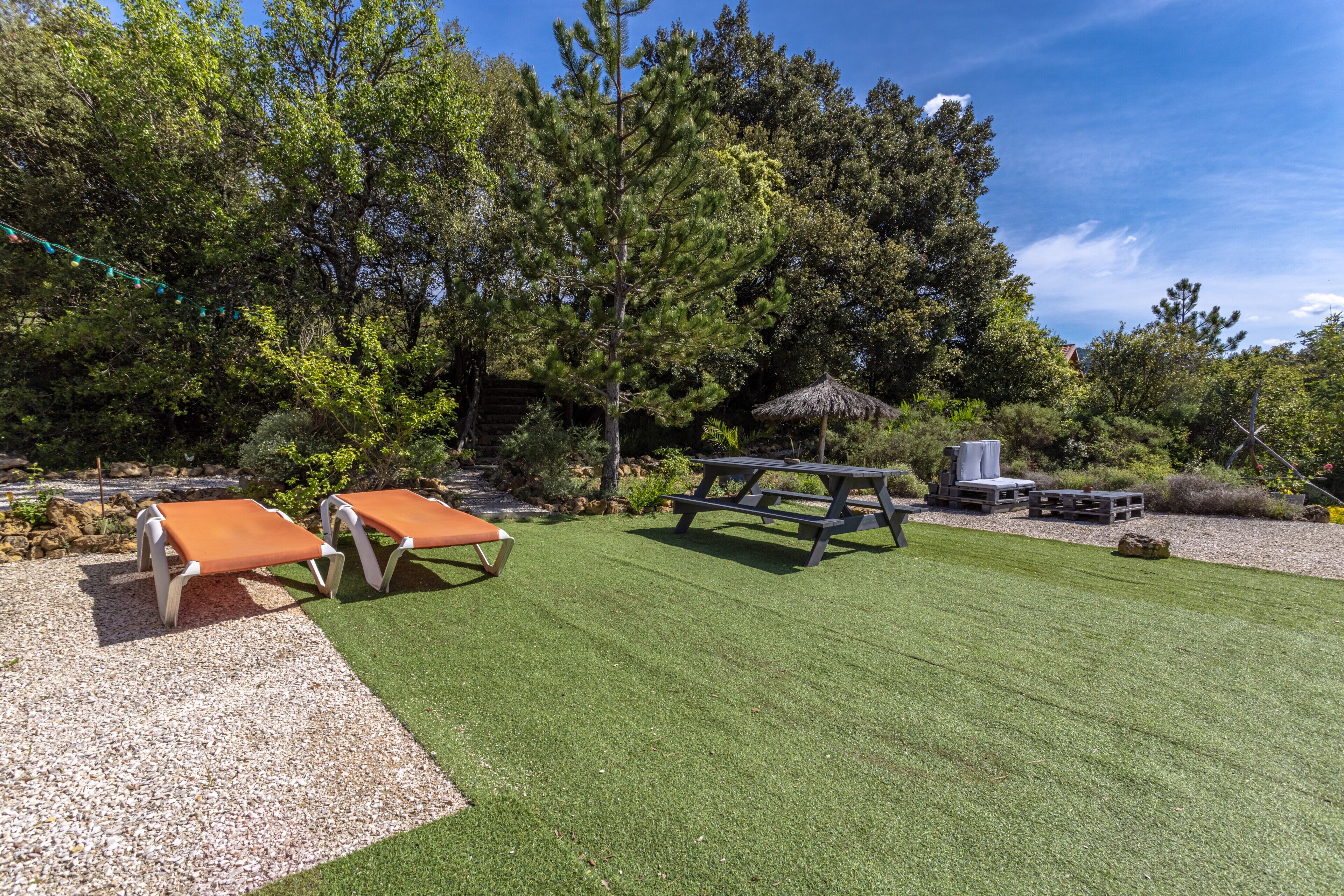 Un patio con dos sillones de descanso, una mesa de picnic y una parrilla.