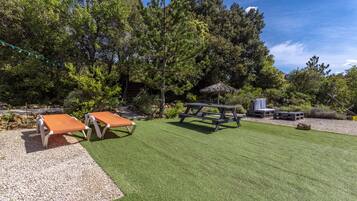 Un patio con dos sillones de descanso, una mesa de picnic y una parrilla.