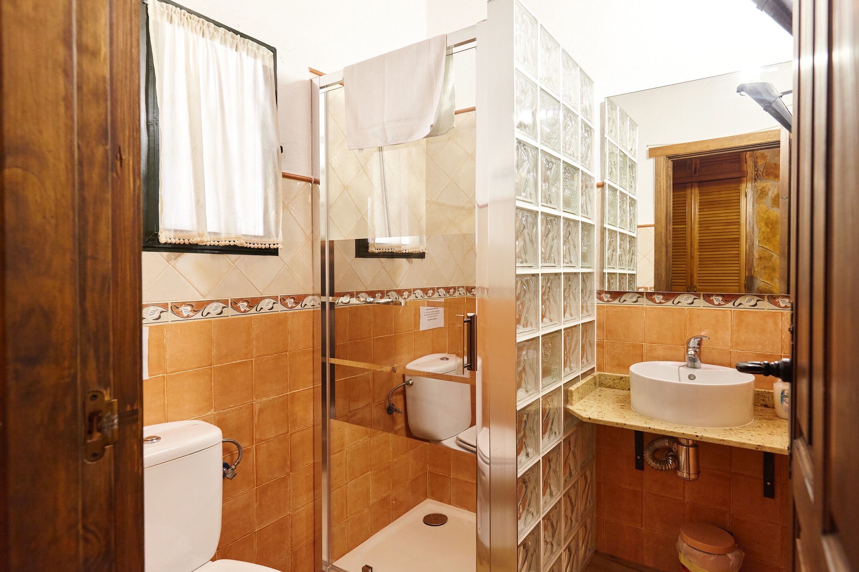 A bathroom with a shower, toilet, sink, and a mirror.