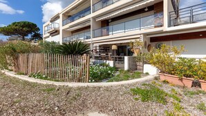 Un immeuble à plusieurs étages doté de balcons, un espace jardin avec des plantes et une clôture, et un ciel dégagé.