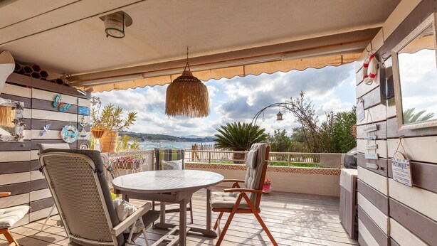 Une terrasse extérieure avec une table et des chaises, un luminaire suspendu et une vue sur la mer.