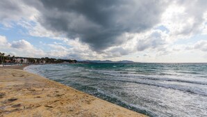 Un paysage côtier avec une plage, des vagues et un ciel nuageux.