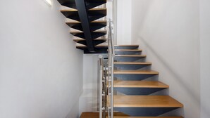 A modern spiral staircase with wooden steps and a metal railing.