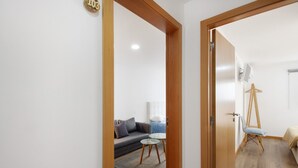 A hallway leading to a living area with a sofa, a small round table, and a tripod stand.