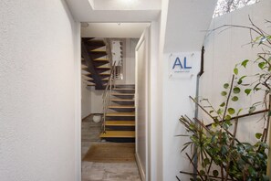 Ein Flur mit Treppe, einer Pflanze und einem Schild mit den Buchstaben 'AL'.
