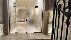 A modern interior with a glass door entrance, a marble floor, and a metal gate. - White Palace Serviced Apartments (New Cairo)