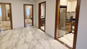 A spacious room with a marble floor, a modern kitchen with a refrigerator and microwave, and a bathroom with a shower and toilet. - White Palace Serviced Apartments (New Cairo)