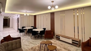 A modern living room with a marble floor, a sofa, a coffee table, and a dining area with chairs and a table. - White Palace Serviced Apartments (New Cairo)