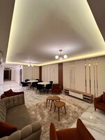 A modern living room with a marble floor, a sofa, a coffee table, and a dining area with chairs and a table.