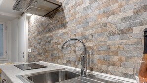 A kitchen with a stainless steel sink, a modern faucet, and a backsplash made of multicolored stone tiles. - Apartment 'Un Bacio A Firenze' with Wi-Fi and Air Conditioning (Firenze)