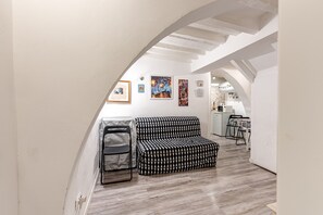 Un intérieur moderne avec un canapé à motifs, une poubelle et des œuvres d’art accrochées aux murs.