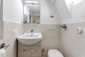 A bathroom with a sink, toilet, and mirror.