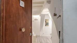 A wooden door with a sign, a white wall with a picture, and a white ceiling with exposed beams. - Apartment 'Un Bacio A Firenze' with Wi-Fi and Air Conditioning (Firenze)