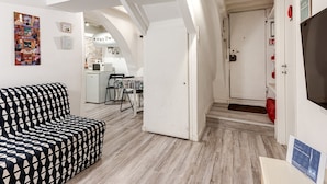 A modern interior with a patterned sofa, a kitchen area, and a door leading to another room. - Apartment 'Un Bacio A Firenze' with Wi-Fi and Air Conditioning (Firenze)