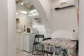 A compact kitchen with a microwave, refrigerator, and a small dining area with a table and chairs.