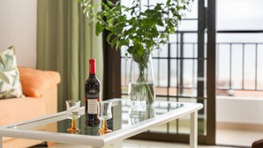 A glass table with a bottle of Merlot wine and two glasses, a vase with green plants, and a view through a window with a metal railing. - Vacation Home 'Casa Ino' with Sea View, Private Terrace and Wi-Fi (Punta del Hidalgo)