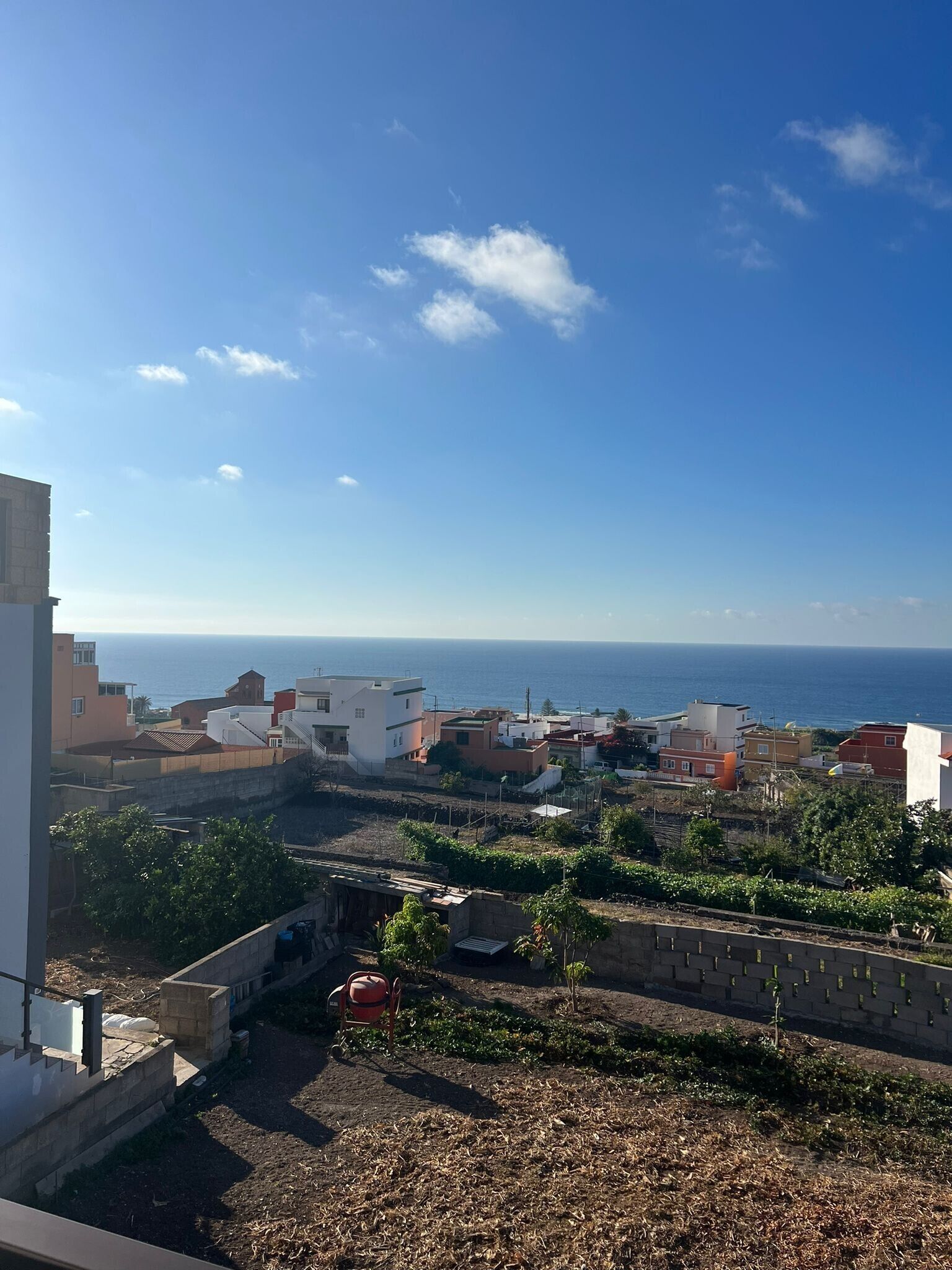 A residential area with a view of the sea, featuring modern buildings and a garden.
