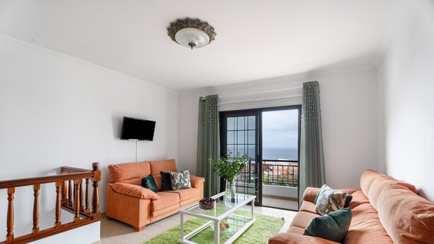 A living room with a sofa, a coffee table, a TV, and a balcony with curtains. - Vacation Home 'Casa Ino' with Sea View, Private Terrace and Wi-Fi (Punta del Hidalgo)