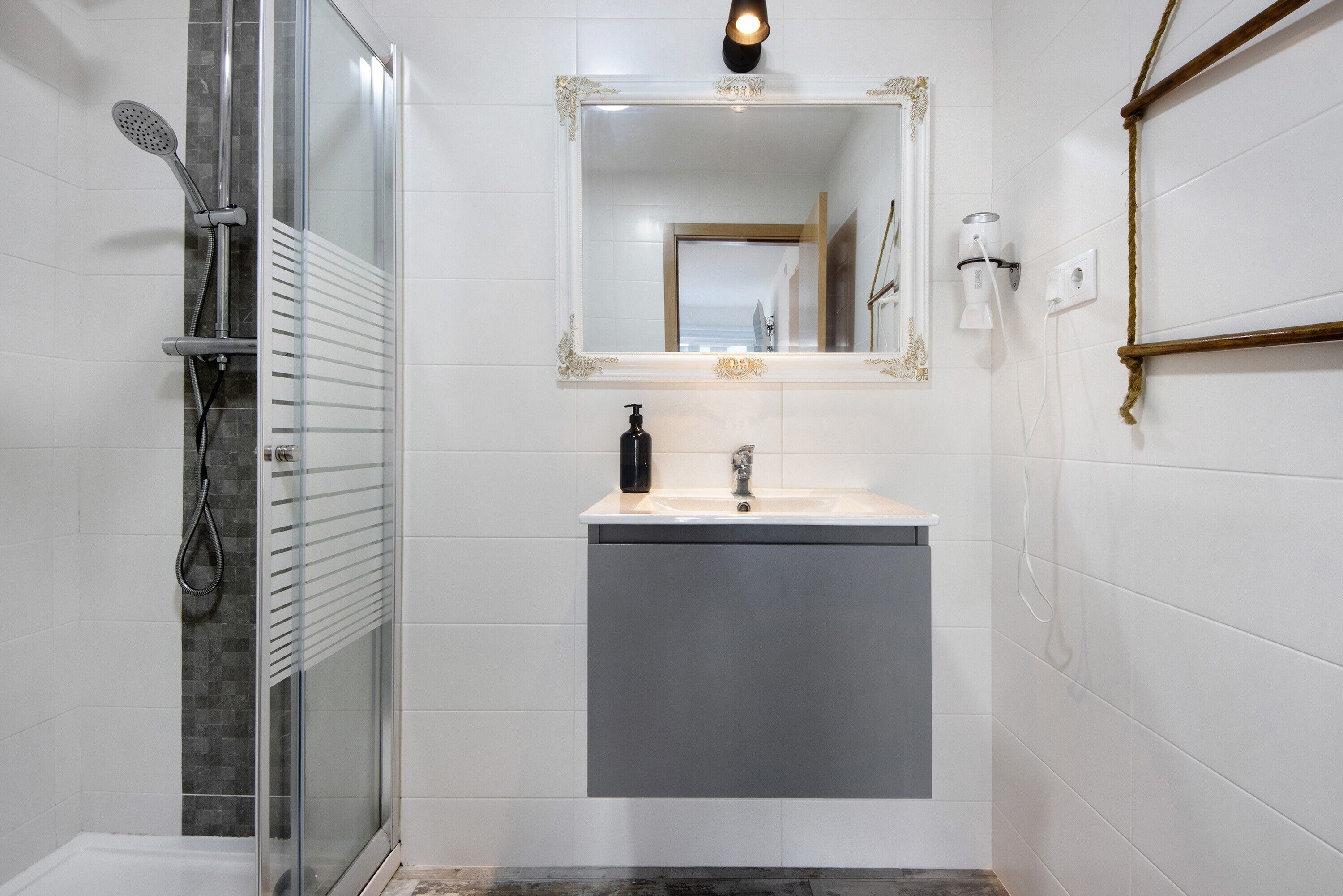 A bathroom with a glass shower enclosure, a vanity with a mirror, and a towel rack.