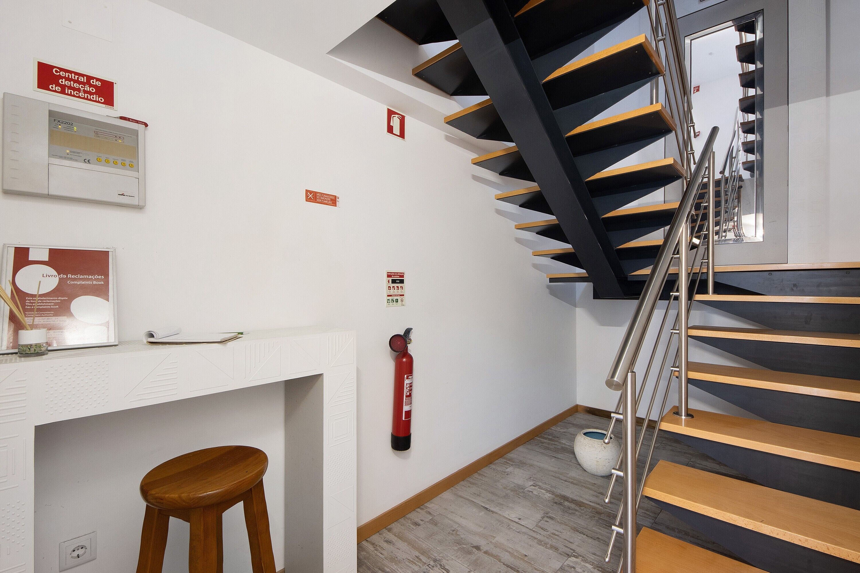 A staircase with a modern design, a fire alarm, and a fire extinguisher mounted on the wall.