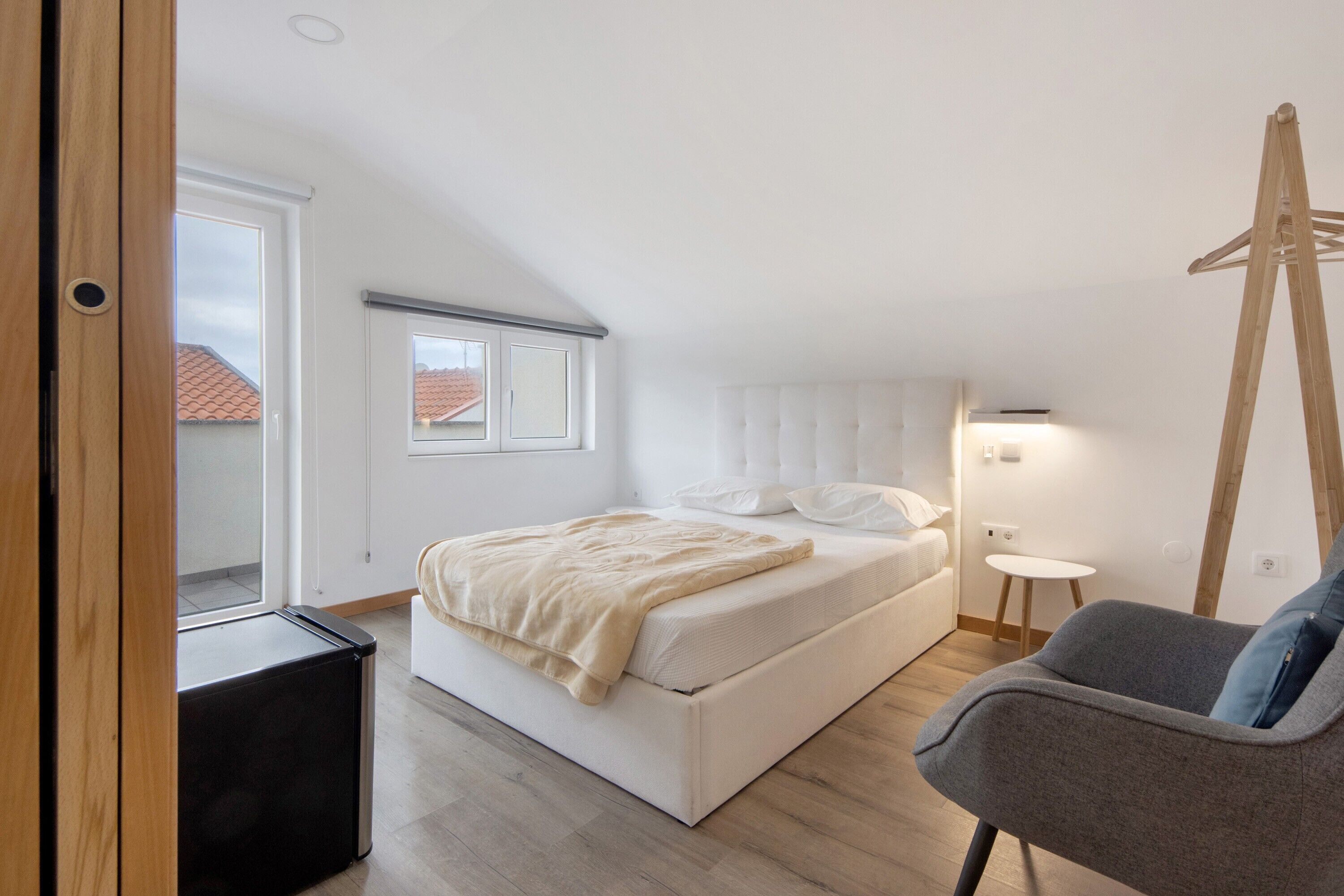 Een slaapkamer met een bed, nachtkastje en stoel.