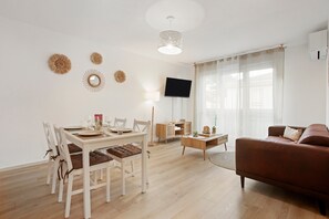 A modern living room with a dining area, a flat-screen TV, and a leather sofa. - A Peaceful Haven – Comfort and Tranquility in the Heart of Fréjus (Fréjus)