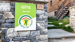 Un muro de piedra con un letrero que dice 'Gîte Savoie' y una casa de madera con el número 476.