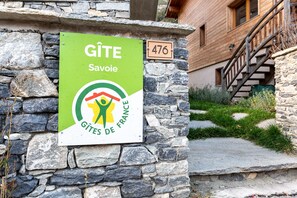 Un muro de piedra con un letrero que dice 'Gîte Savoie' y una casa de madera con el número 476.