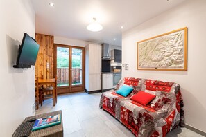 Un espai habitable compacte amb sofà, televisió, zona de menjador i cuina.
