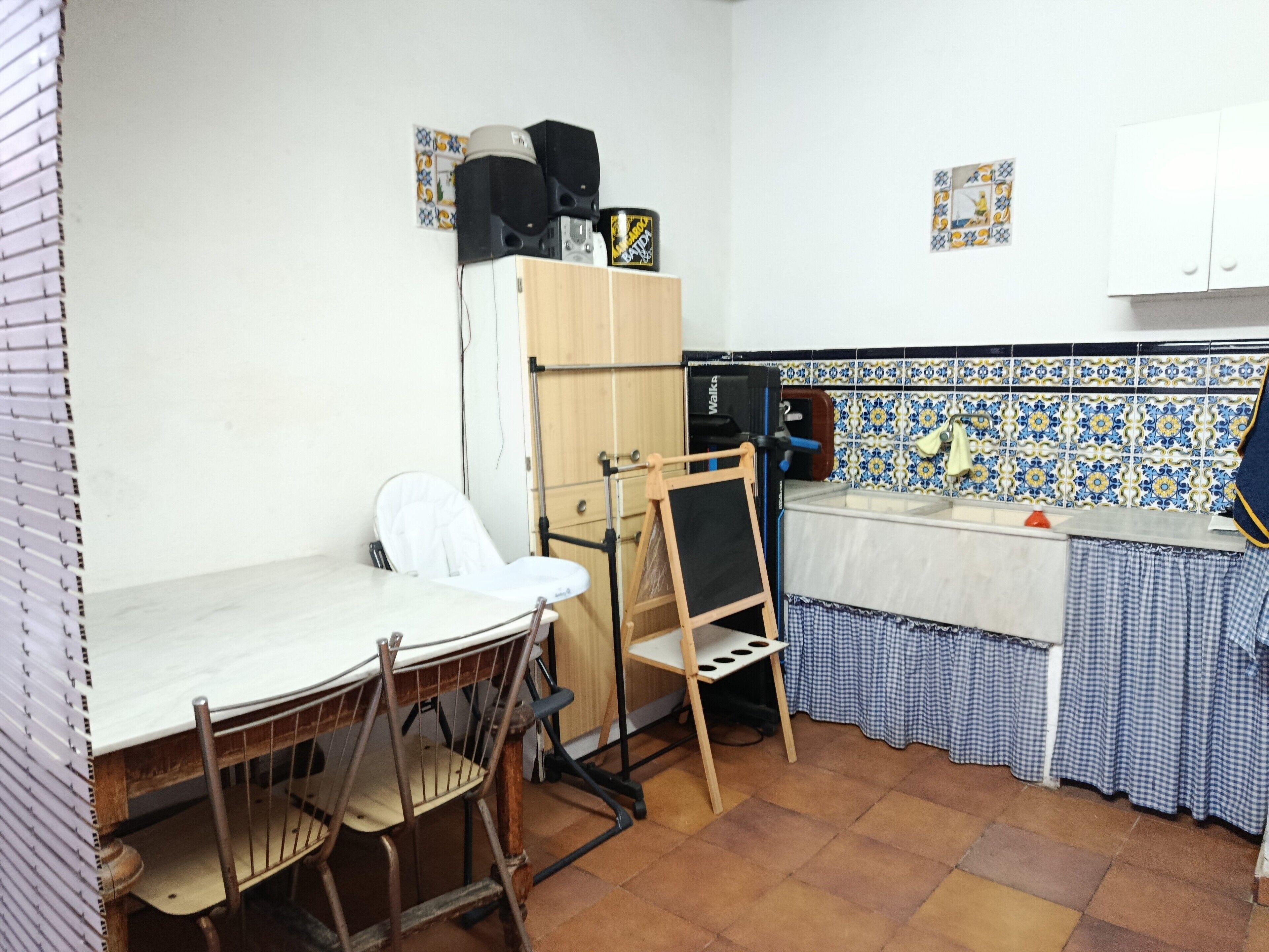 A compact kitchen with a wooden table, chairs, a small refrigerator, and a tiled backsplash.
