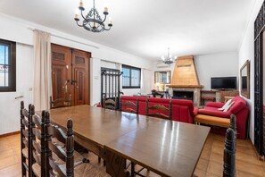 Ein Essbereich mit Holztisch und Stühlen, einem roten Sofa, einem Kamin und einem Fernseher.