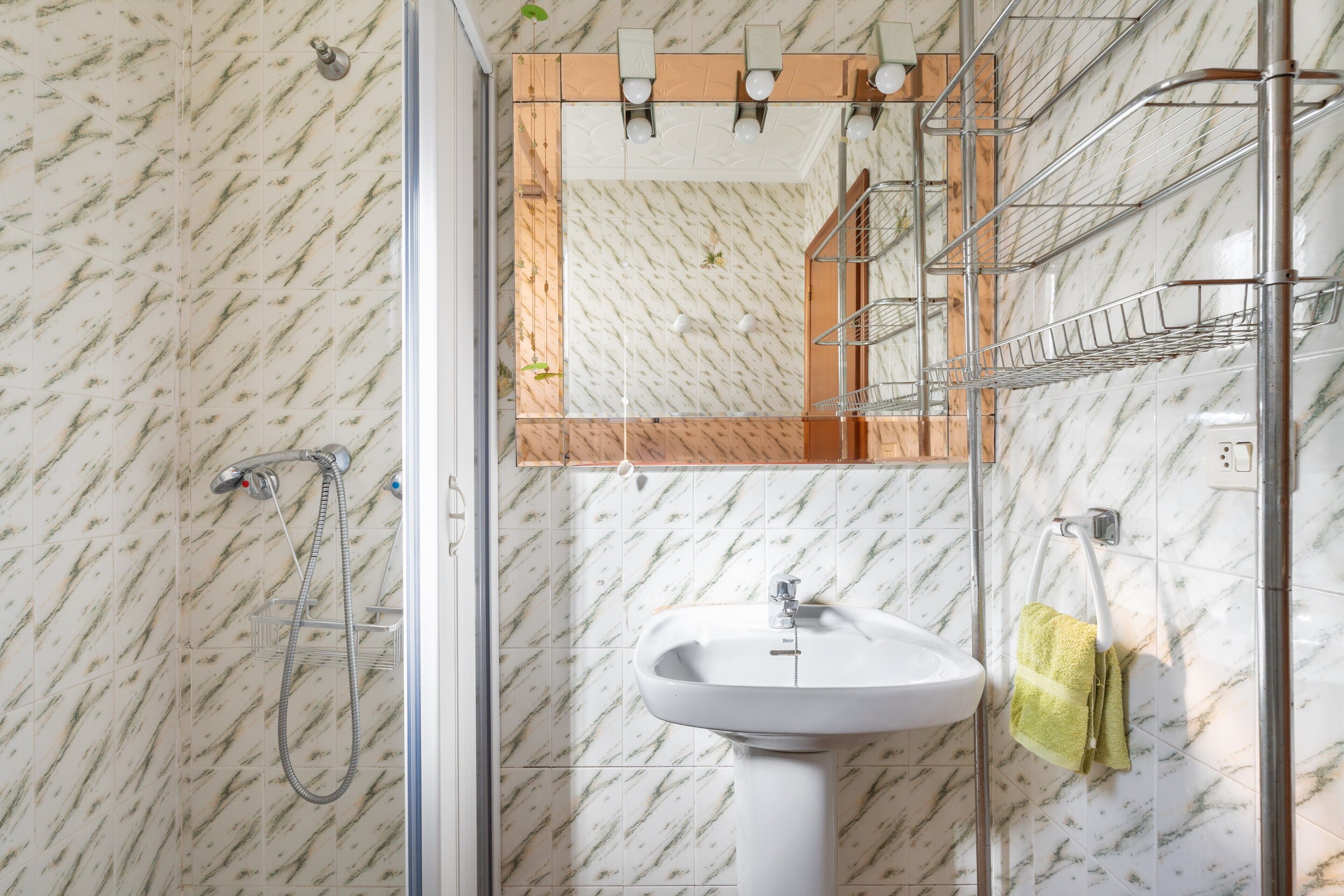 Un baño con ducha, lavamanos y espejo.