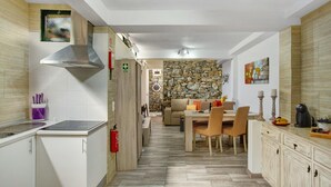A modern kitchen with a stove, sink, and a stone wall in the background.