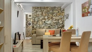 A modern living room with a stone wall, a sofa, a dining table, and chairs.