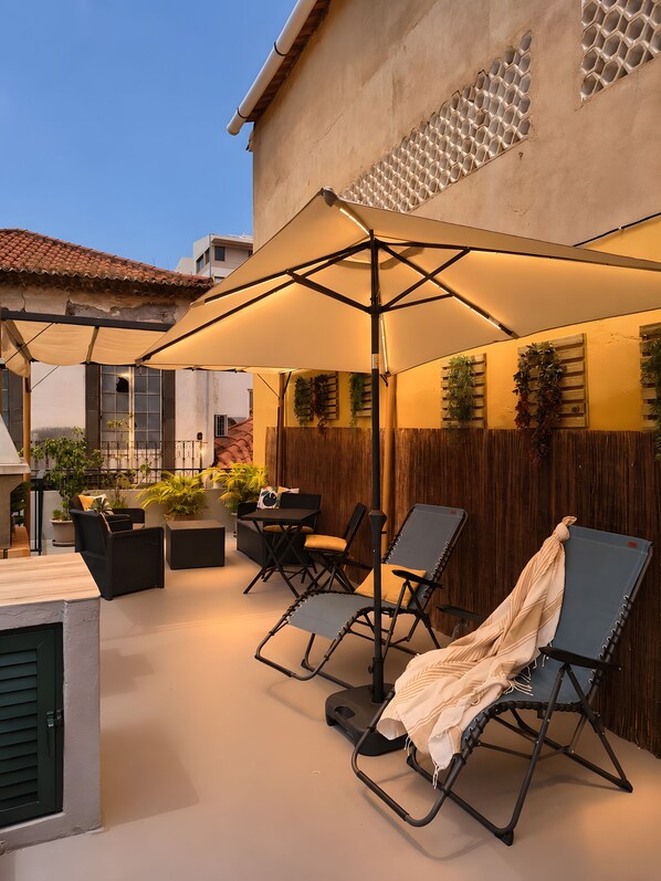 An outdoor patio with a table, chairs, and a large umbrella. - Apartment 'Host Albina' with Private Terrace, Wi-Fi and Air Conditioning (Funchal)