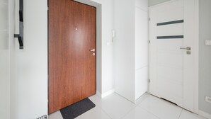 A hallway with a wooden door and a white door with horizontal lines. - Warszawa Rakowska Cosy Apartment (Warszawa)