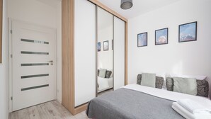 A bedroom with a bed, a wardrobe, a mirror, and three framed pictures on the wall. - Warszawa Rakowska Cosy Apartment (Warszawa)