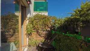 Eine Holzterrasse mit Stuhl, Tisch und einem Blumentopf.