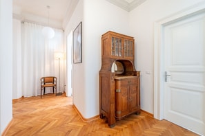 Ein Flur mit Holzboden, einem Schrank mit Glastüren, einem Stuhl, einer Lampe und einer Tür.