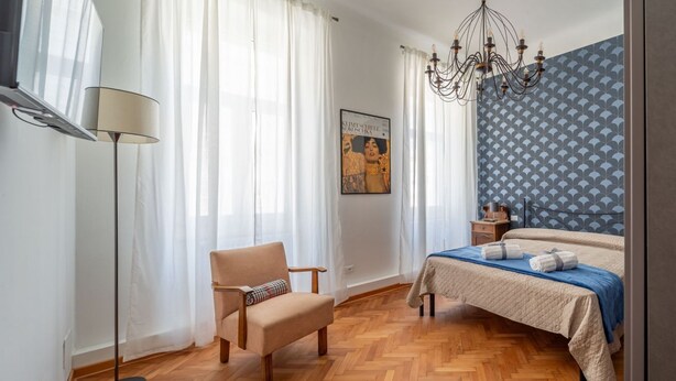 Un dormitorio con cama, una silla, una lámpara de pie y un candelabro.