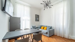 Una sala de estar moderna con una mesa de comedor, sofá y televisor montado en la pared.