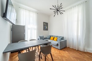 En moderne stue med spisebord, sofa og et TV ophængt på væggen.